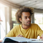 A therapist studies relationship therapy materials at a desk with books, notes, and a laptop while preparing to apply new skills with clients.