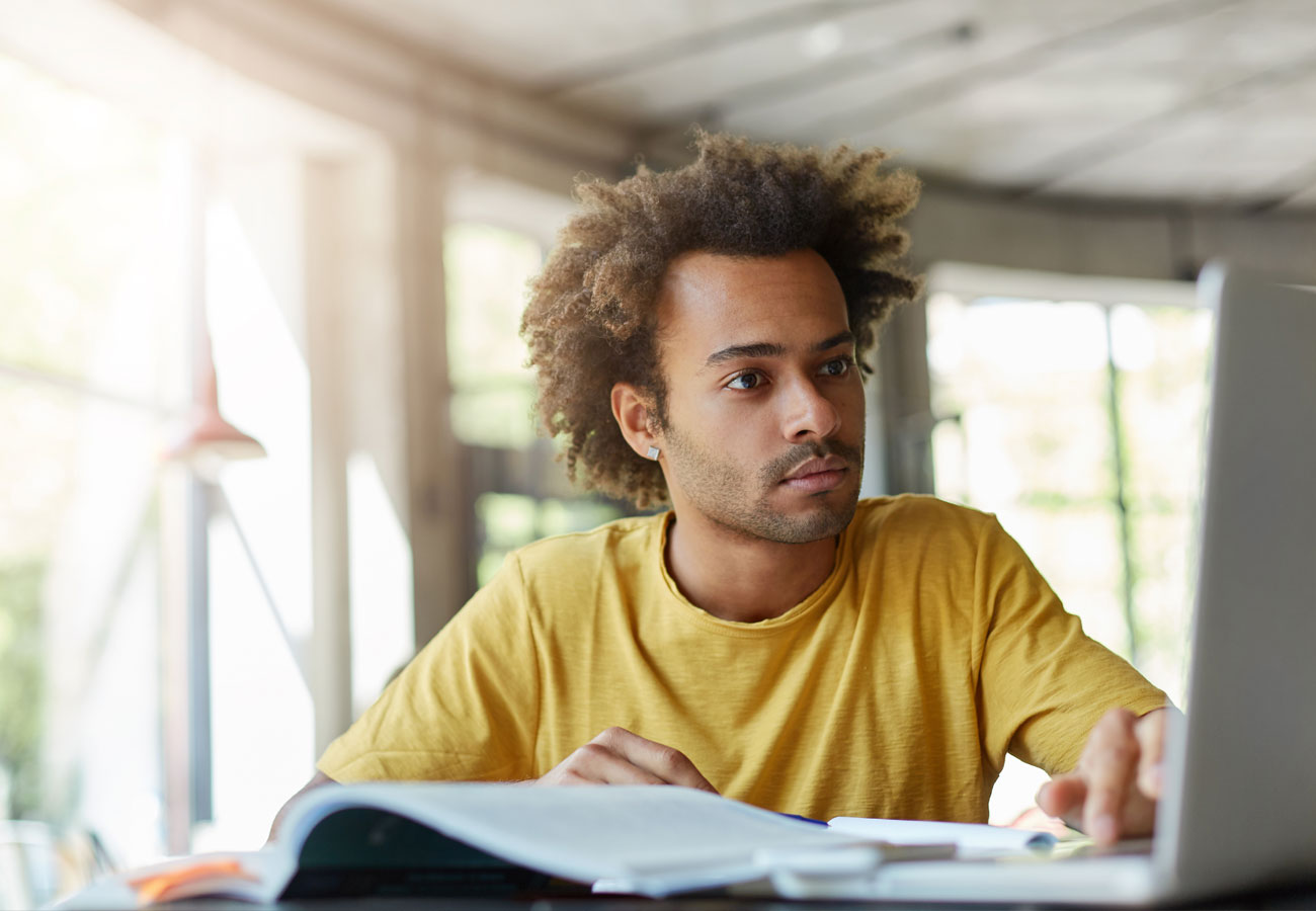 A therapist studies relationship therapy materials at a desk with books, notes, and a laptop while preparing to apply new skills with clients.